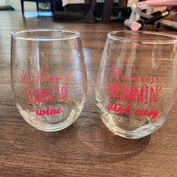 set of two stemless wine glasses with pink 
 text on glass  "It's Mom's turn to wine."
 "Mommin' ain't easy