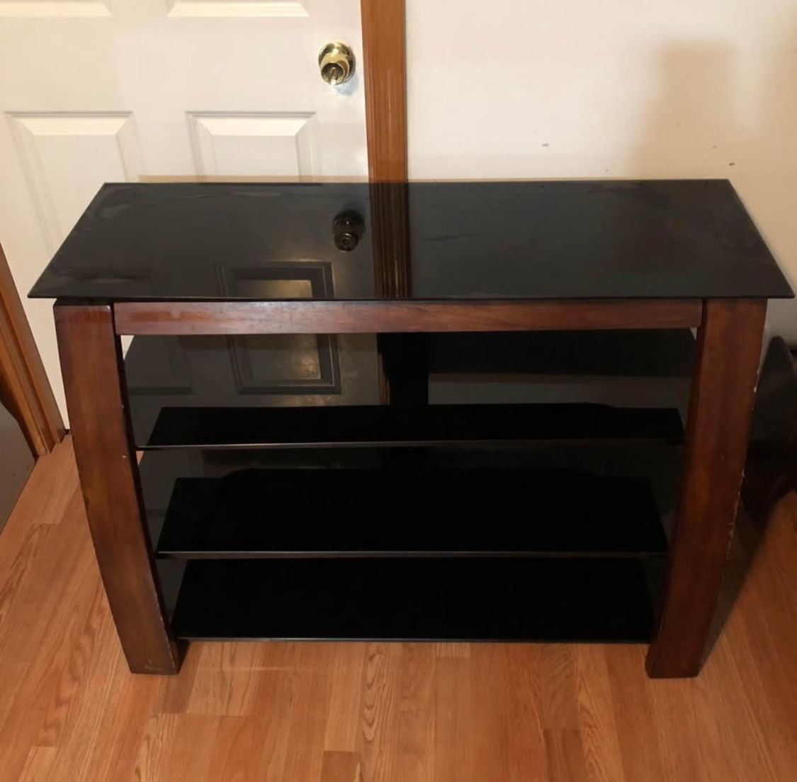 TV-Media console with 4 black layers and brown wood legs. There is a little scratch. Dimension: 44”L x 16”W x 30”H