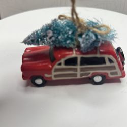 A Christmas tree decoration in the shape of a red station wagon with an official Christmas tree.