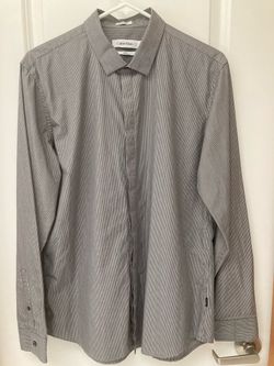Brand New! Calvin Klein slim fit button-down dress shirt in a gray and white fine pinstripe pattern. Long sleeves with button cuffs and a spread colla