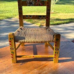 Vintage Mexican folk art children's chair with a woven seat and hand-painted decorations.