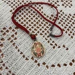 a necklace with a carved pendant featuring two roosters and a Chinese "double happiness" symbol.