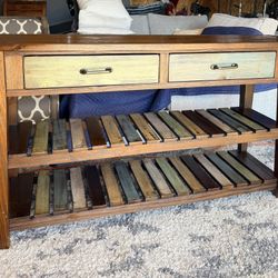 Design by Ashley Mestler rustic brown sofa table with multicolored shelves.