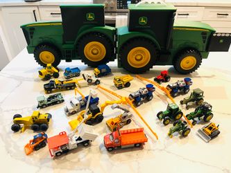 John Deere branded farm vehicles, likely from the ERTL "Carry Case Value Set" or "Farmin' Friends Hauling Set".The set includes a large, tractor-shape