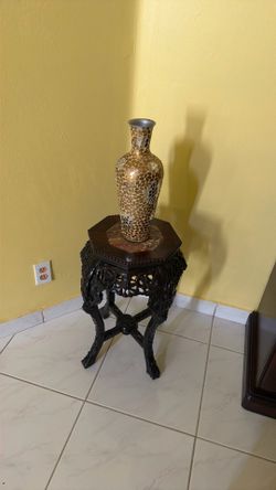 Small dark wooden table with a golden vase
