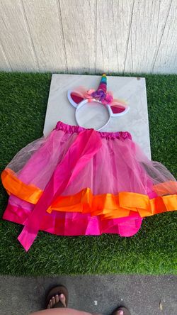 falda tutú de tul en capas en tonos rosa y naranja con un lazo grande y una diadema temática de unicornio a juego.