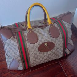 Elegant Gucci duffel bag with beige and yellow design. Features signature pattern and green-red accents.