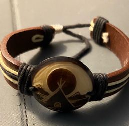 unisex bohemian-style multi-layer leather bracelet featuring an adjustable drawstring cord closure and a center focal piece.
