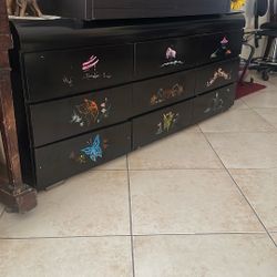 Black wooden dresser with Asian-inspired artwork  