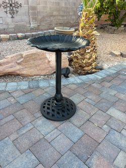 Black metal pedestal birdbath with a scalloped flower-shaped basin and an open lattice-pattern base.