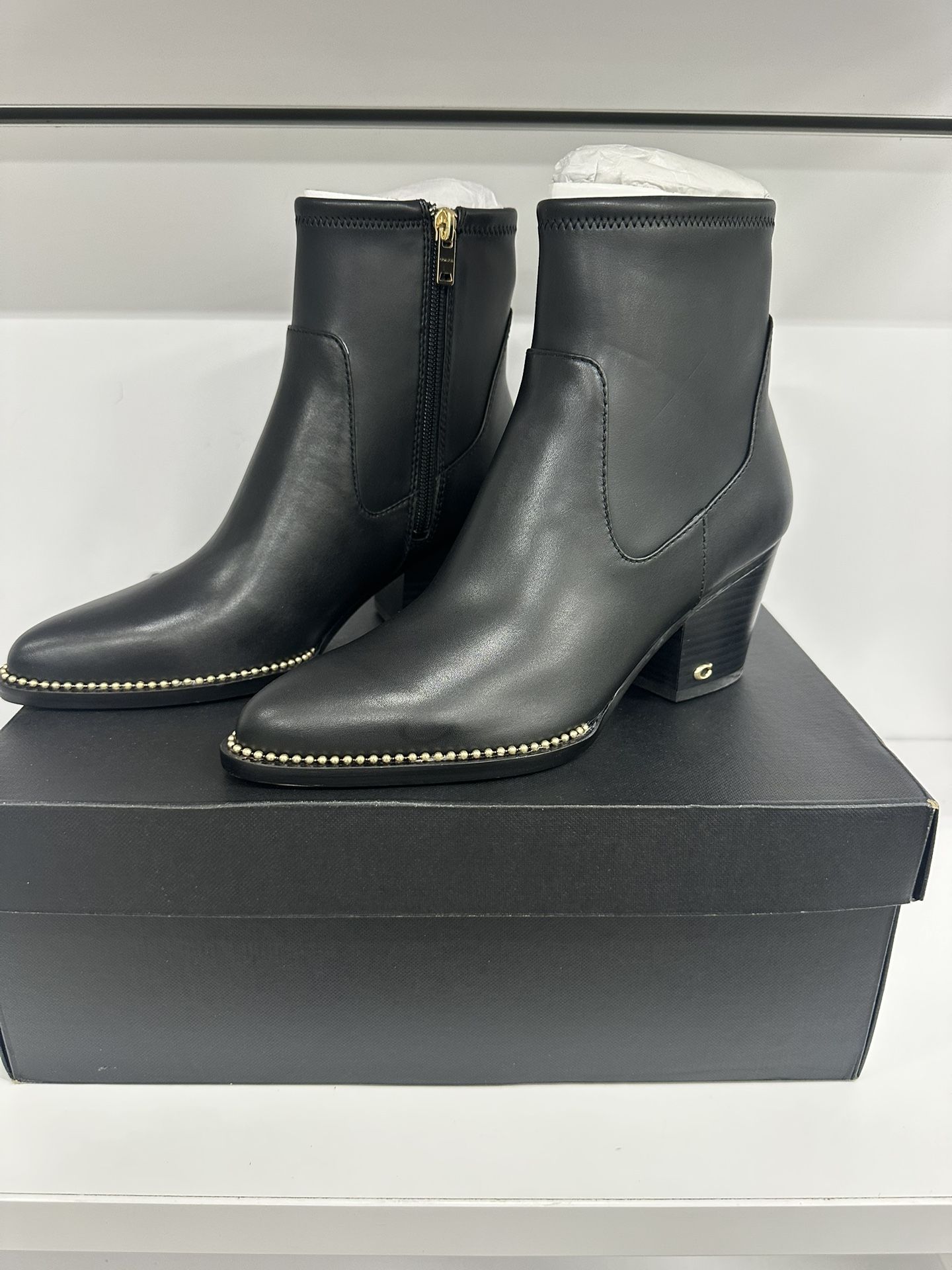 black leather Coach Pell booties with gold stud detailing. 
