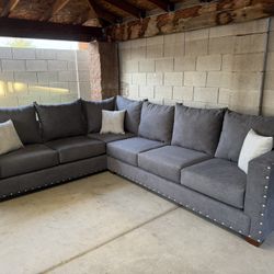 8x10 “L” sectional new in plastic gray fabric with silver nail heads