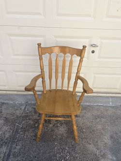 Solid wood captain's chair has a light oak finish. This Windsor-style armchair