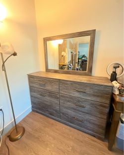 Signature Design by Ashley Ralinksi 6-Drawer Dresser featuring a rustic warm gray wood-grain finish and a matching rectangular wall mirror.