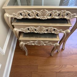 Elegant gold nesting tables with glass tops and ornate detailing.