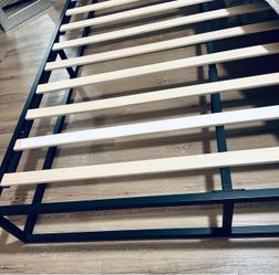 Black metal queen sized bed frame with wooden slats