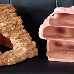 Pair Of Gecko Habitats. One With Slats Is Made Of Rock. The Other Is Plastic.