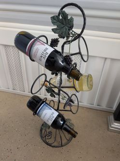 Muted green leaf wine rack w/three bottles of wine.