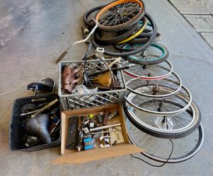 A collection of assorted bicycle parts including wheels, tires, seats, handlebars…..