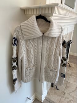 Beautiful chunky cable knit sweater cardigan in a soft cream color with a cozy oversized collar and full zip front. Features unique patterned sleeves 