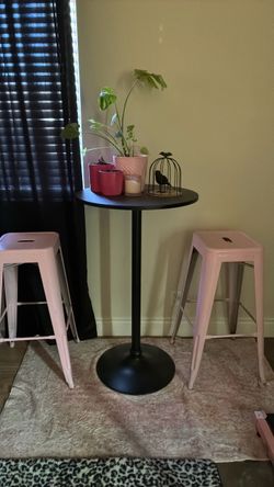 Black cocktail table with two pink barstools