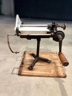 Vintage antique manual bread slicer with hand-crank operation and adjustable slicing mechanism.
