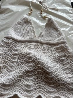 Handmade look crochet halter tank. Scalloped neckline with knotted tie and wooden bead accents. Soft ivory color and wavy crochet pattern. Lightweight