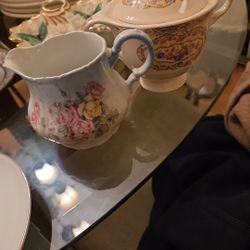 The items are porcelain or bone china teaware, specifically a creamer or milk jug with a floral design
