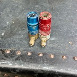 The object in the image is a red R134a quick coupler adapter, used for automotive air conditioning systems. 