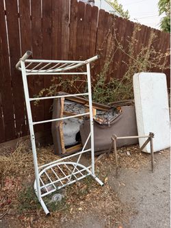 White metal toddler bed with mattress in alley behind 123 Oak st Modesto