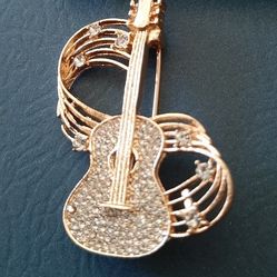 Guitar-shaped brooch with sparkling crystals.