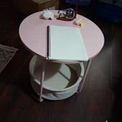 Small round pink side table with basket on bottom 