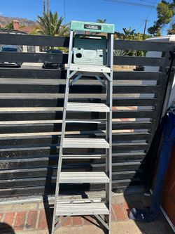 Durable aluminum step ladder from Gorilla Ladders has six steps and a green plastic top cap. This lightweight ladder is constructed with a foldable de