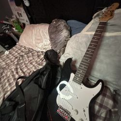 electric guitar with amp and extra strings in bag