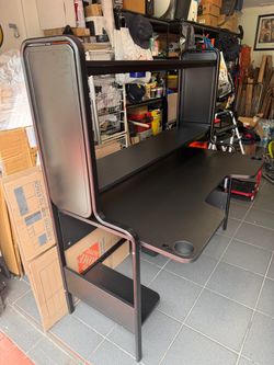 IKEA Fredde Gaming Black L-shaped desk with built-in shelves and cup holders.