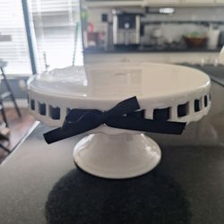 White porcelain cake stand, decorative black ribbon.
