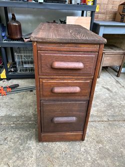 Antique wood 3 drawer file cabinet on wheels.