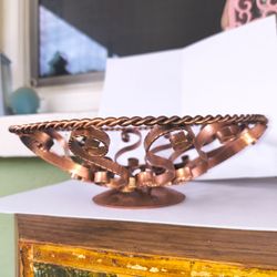 Beautiful copper-toned decorative metal bowl with scrollwork patterns