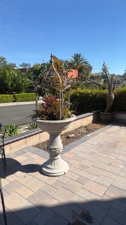 This decorative concrete bird bath planter features a classic pedestal base and a distinctive wrought iron cage