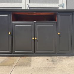 Modern black TV stand / media console with gold hardware.
