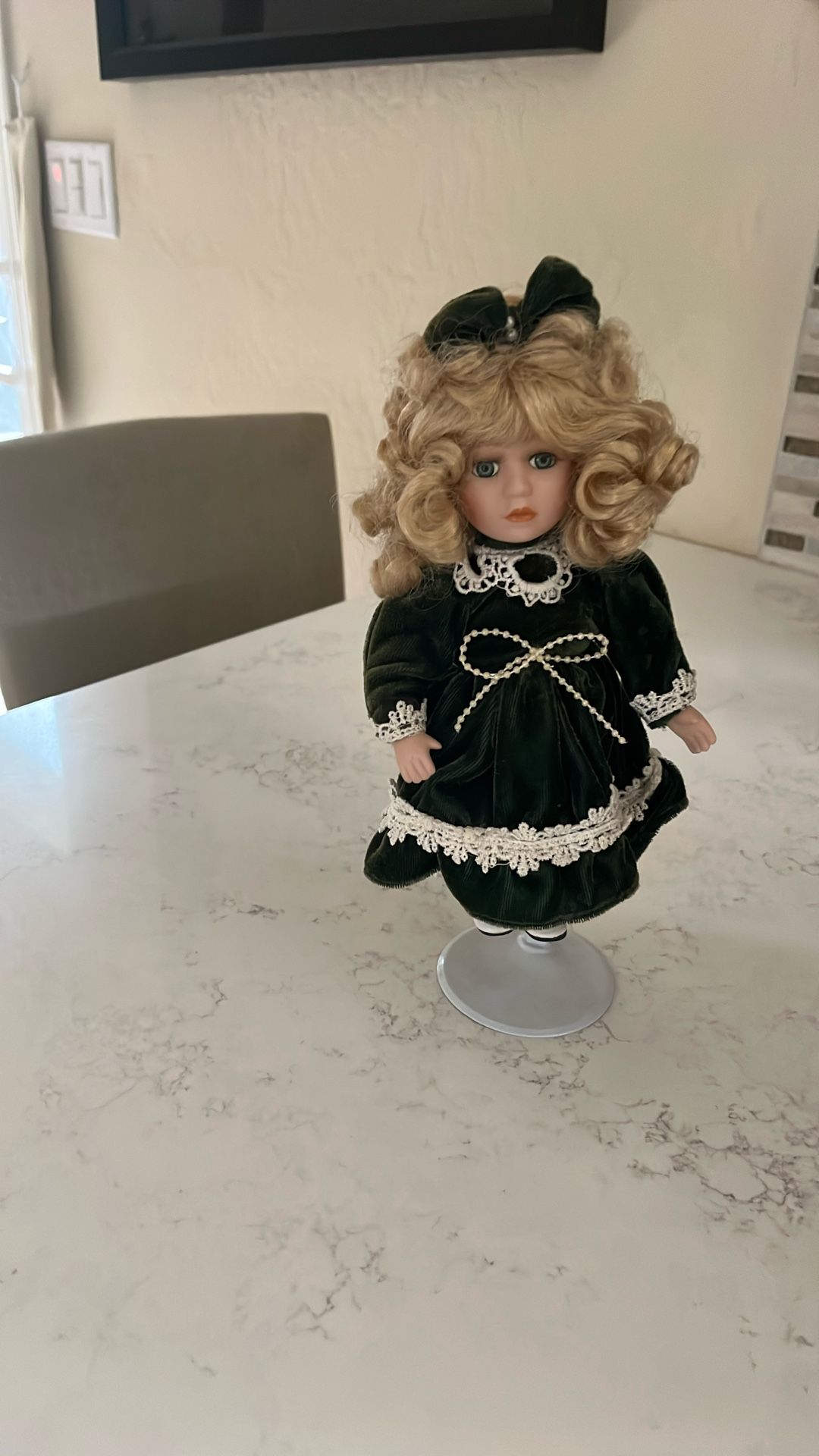 Porcelain doll. Blonde hair and velvet green dress