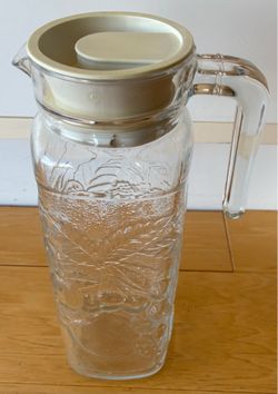 Glass pitcher, raised fruit design, square with plastic lid. 9 1/2” tallX3” wide.