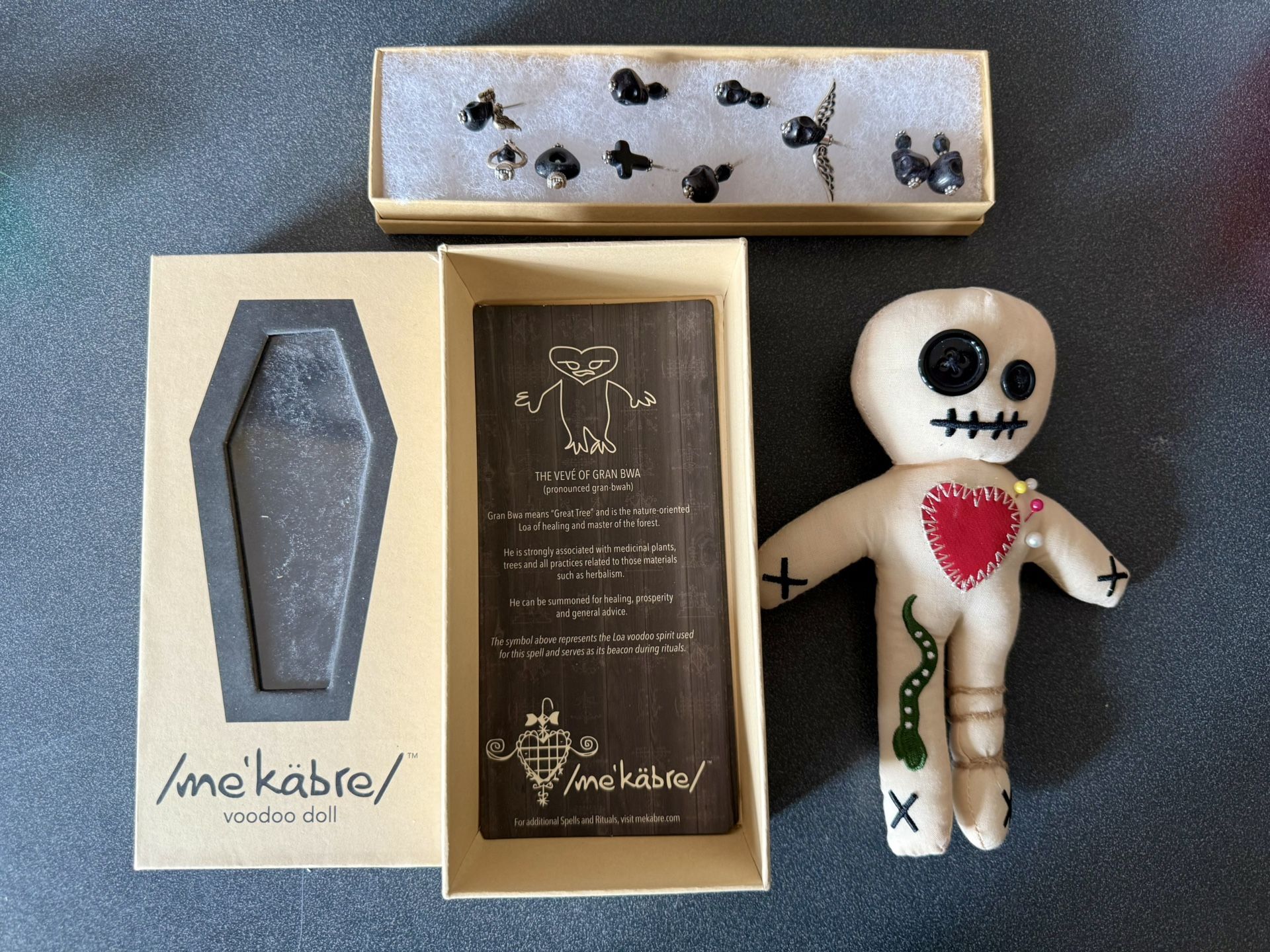 The kit includes a voodoo doll, a coffin-shaped box, and pins