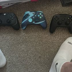 Two Xbox 360 controllers and another controller that is stills series