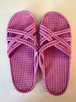 These are pink woven slide sandals featuring an open-toe crisscross rope design and molded footbeds