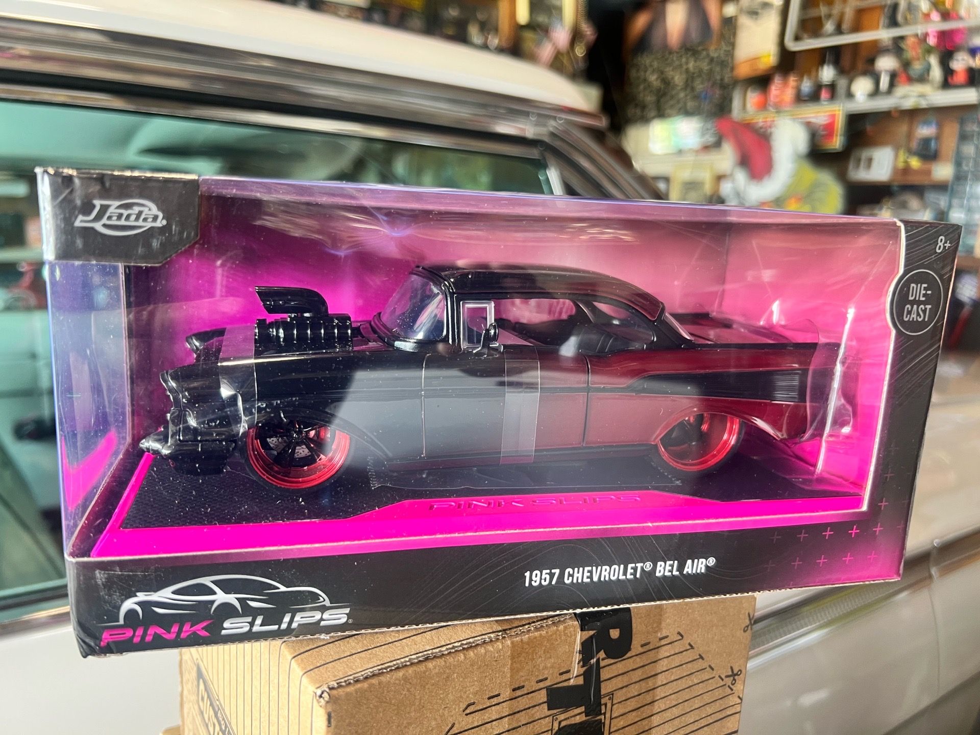 This is a Jada Toys 1:24 scale diecast 1957 Chevrolet Bel Air from the Pink Slips series in black and red.