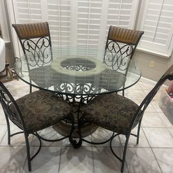 BEAUTIFUL DINETTE GLASS TABLE (48 INCH RIUND  WITH STONE BASE - 4 WROUGHT IRON CHAIRS WITH UPHOLSTERED SEATS - PRICE IS FIRM