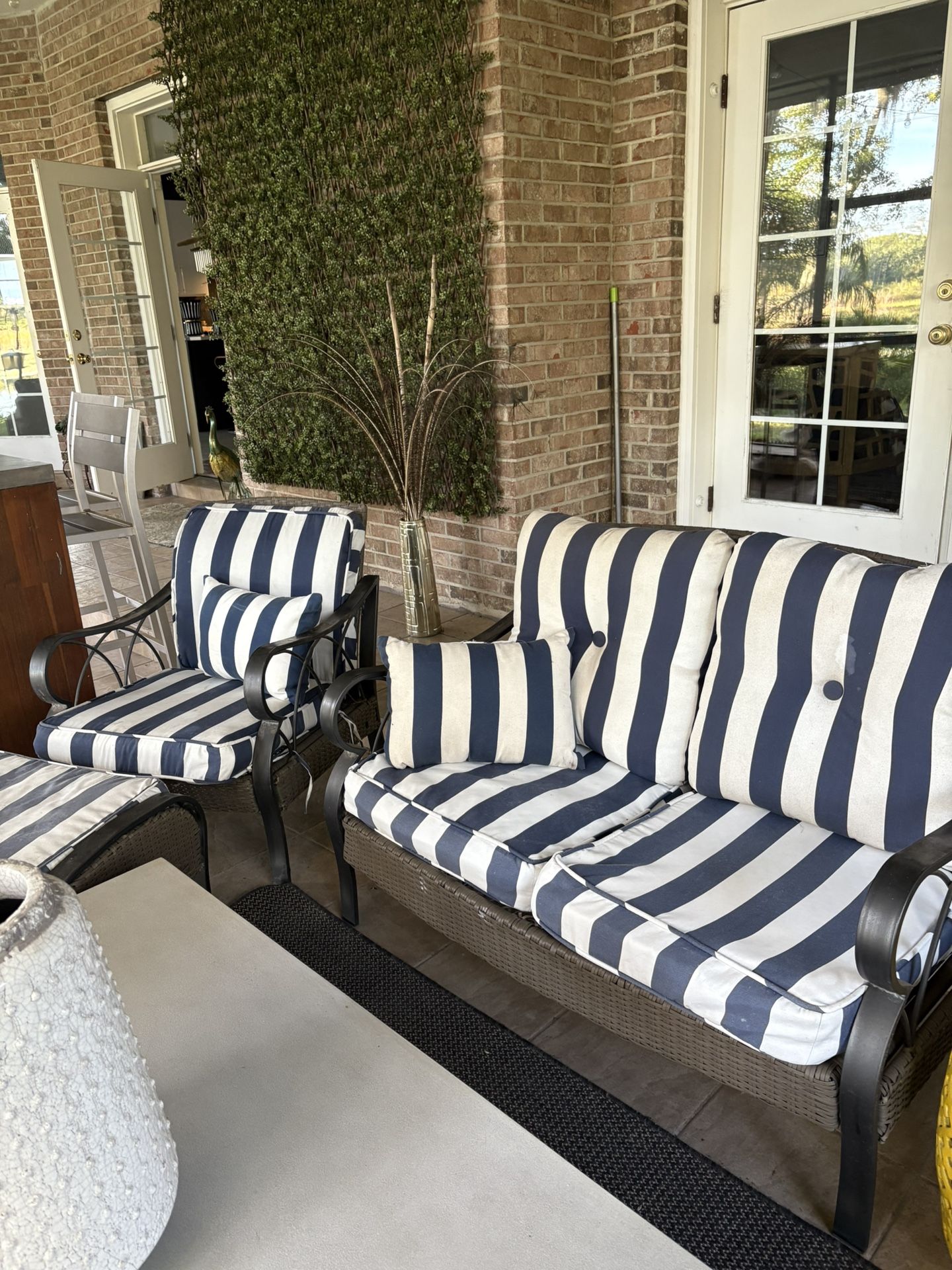 Outdoor loveseat with cushions and side chair with ottoman matching