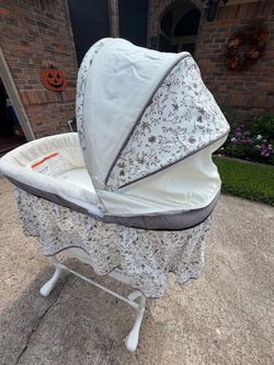 Elegant baby bassinet with a floral pattern and canopy.