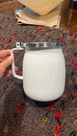 vintage white enamelware pitcher with a stainless steel lid and handle, often used as farmhouse kitchen decor or for serving beverages